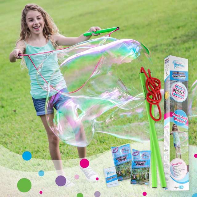 Young girl in grass with a bubble wand creating large bubbles. Product packaging in lower right corner.