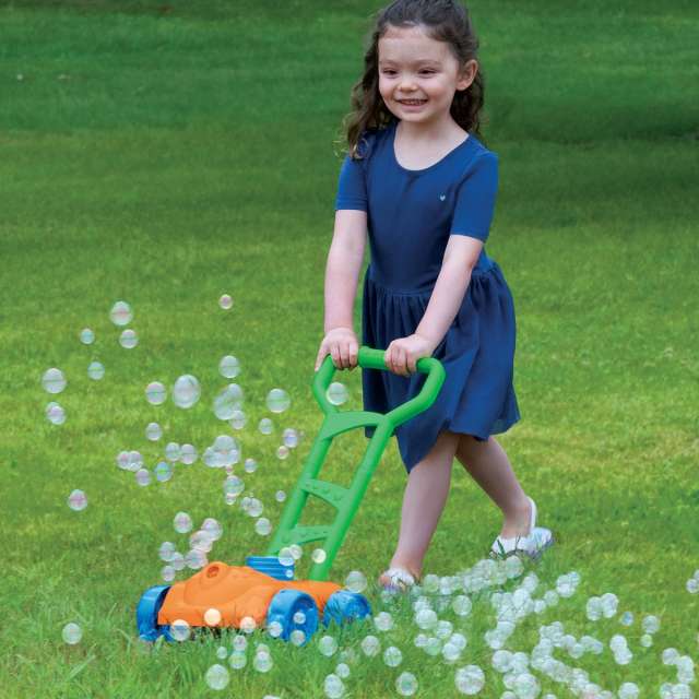 Young girl pushing toy lawn mower that is blowing bubbles